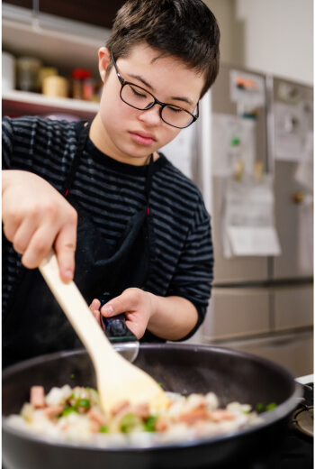 Asian teenage boy cooking, for information on orthdontics for Down's Syndrome, autism, and special needs.