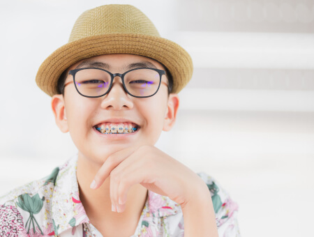 Young Asian teenage boy wearing braces and smiling - for information on orthodontic emergencies